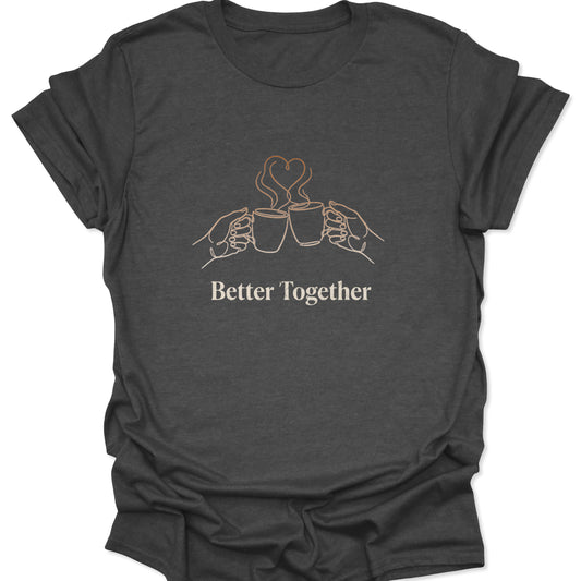 Graphic tee featuring tan line art of two coffee mugs clinking with heart-shaped steam and "Better Together" text on a dark heather gray background.