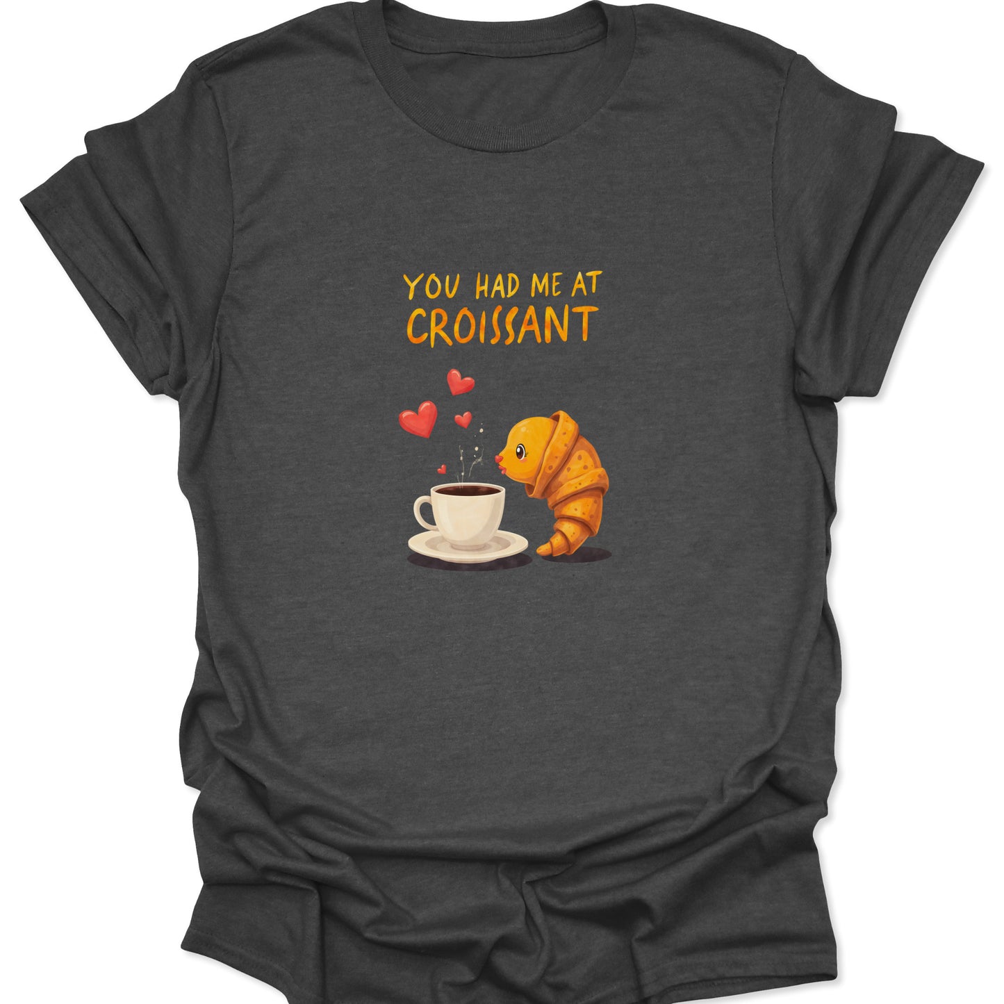 Dark heather gray tee shirt with a cute, anthropomorphic croissant illustration next to a cup of coffee. High-signal SEO alt text for a coffee and pastry lover's t-shirt.