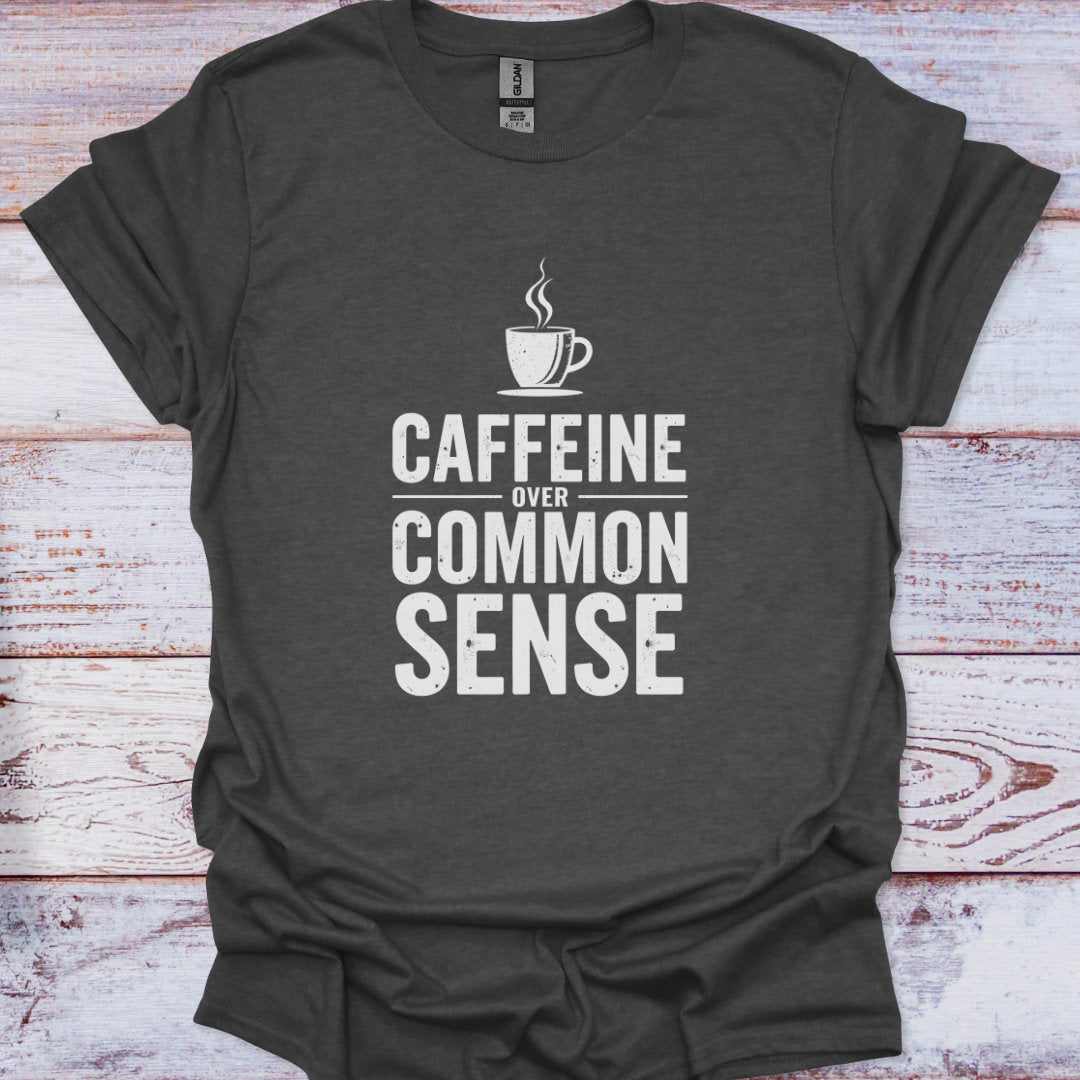 Dark gray t-shirt with 'CAFFEINE OVER COMMON SENSE' text and coffee cup graphic on a wooden surface.