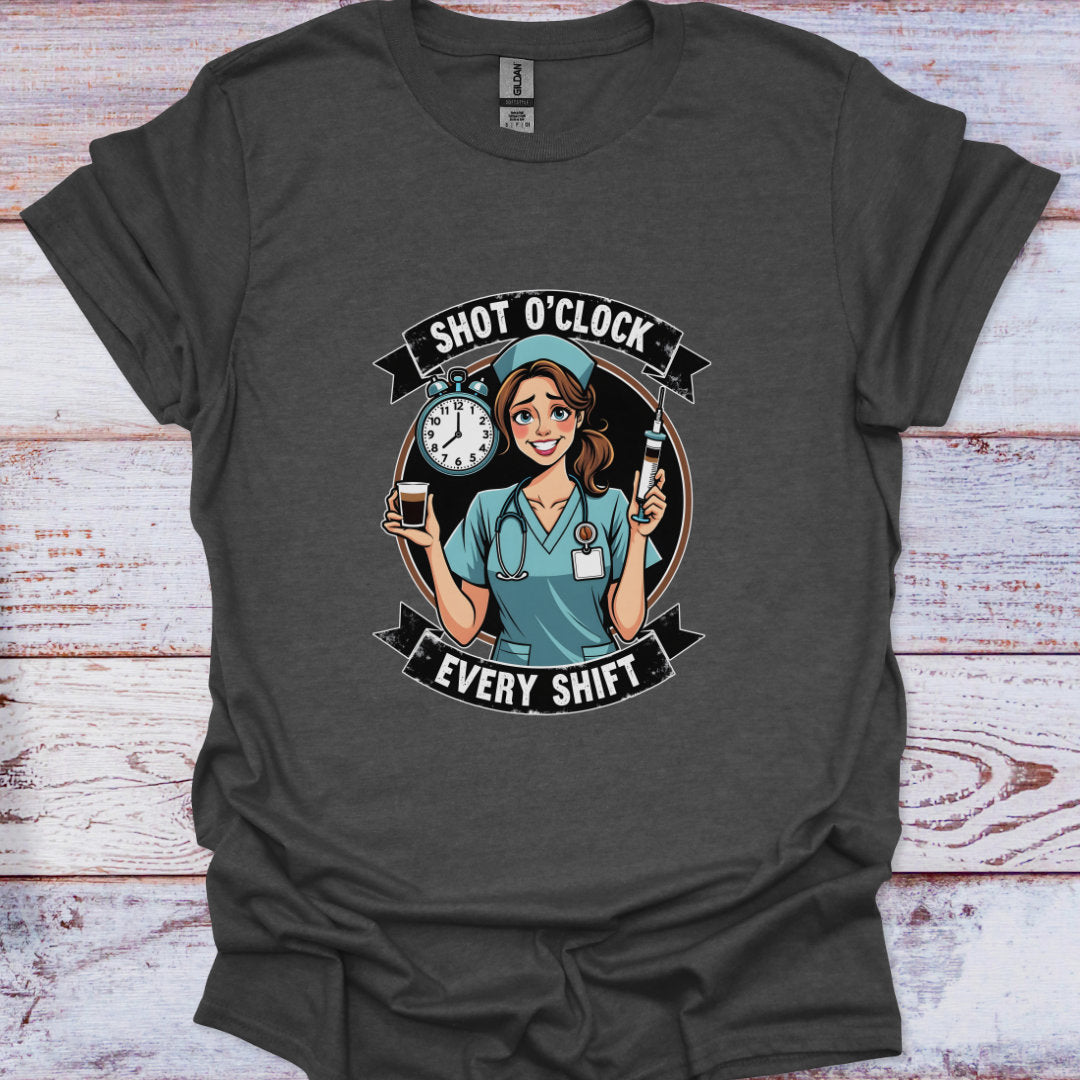 Dark gray t-shirt with a graphic of a nurse holding a clock and a bottle, text 'Shot O'Clock Every Shift', on a wooden surface.