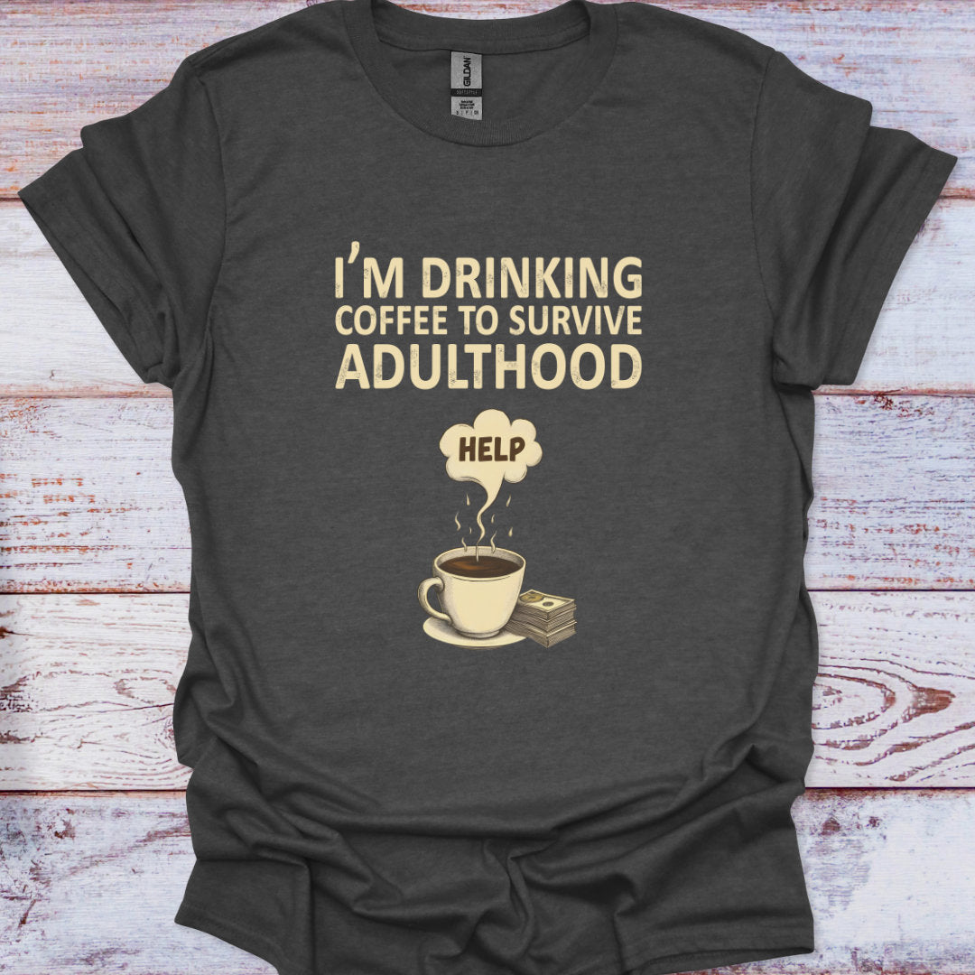 Dark gray t-shirt with a graphic of a coffee cup and money, text 'I'm drinking coffee to survive adulthood HELP' on a wooden surface.