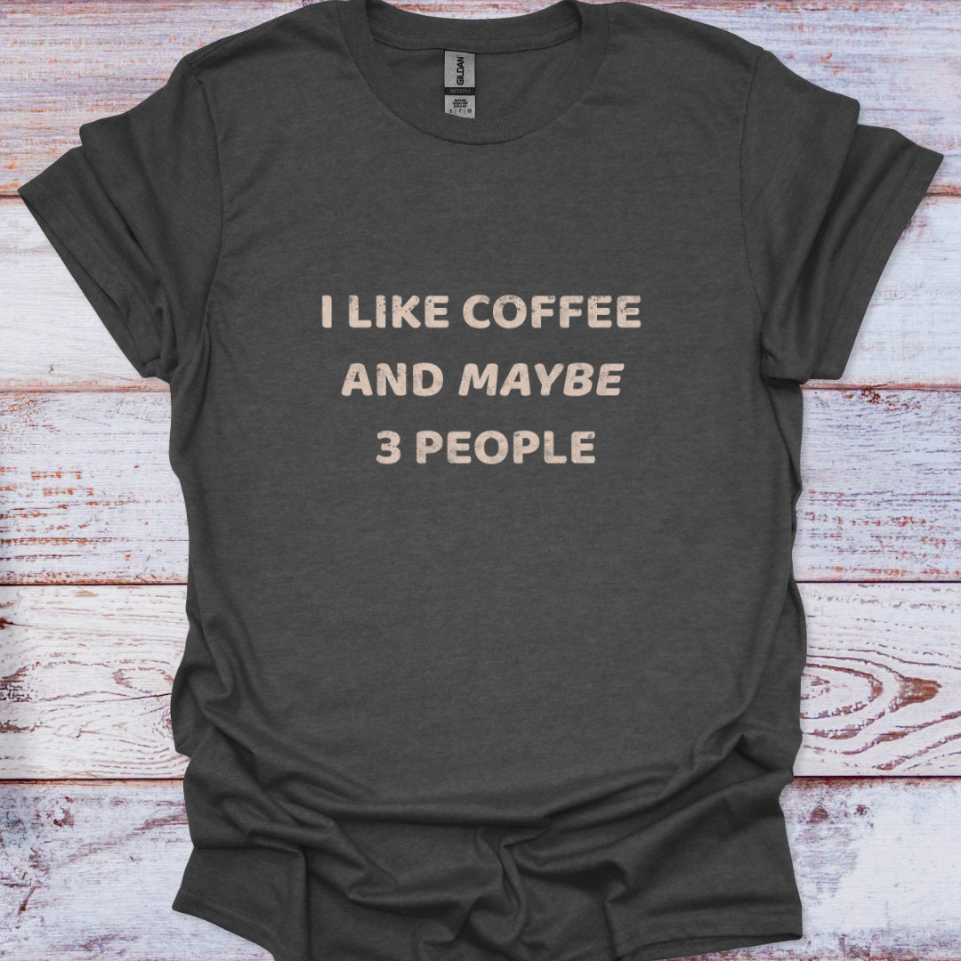 Dark gray t-shirt with 'I LIKE COFFEE AND MAYBE 3 PEOPLE' text on a wooden surface