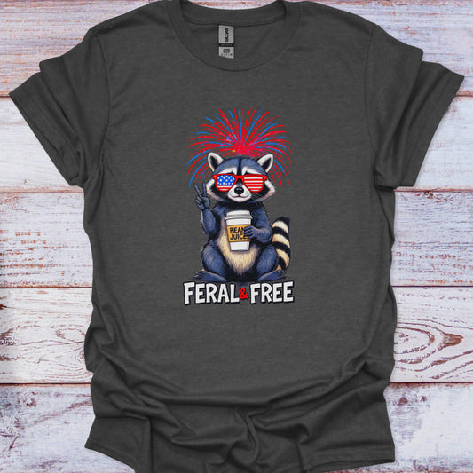Gray t-shirt with a raccoon graphic and 'Feral & Free' text on a wooden surface