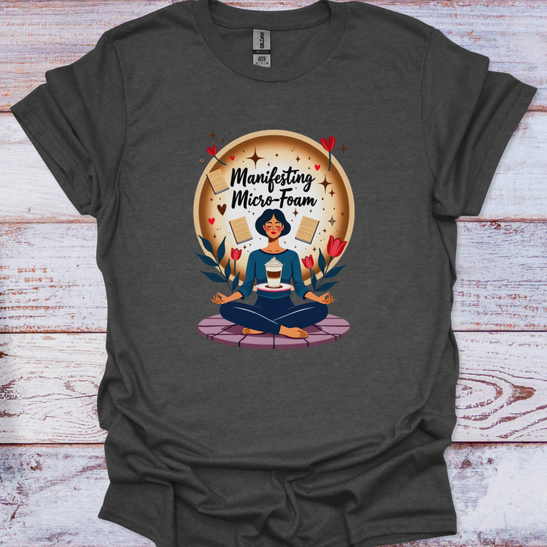 Dark gray t-shirt with a graphic of a person meditating and text 'Manifesting Micro-Foam' on a wooden surface.