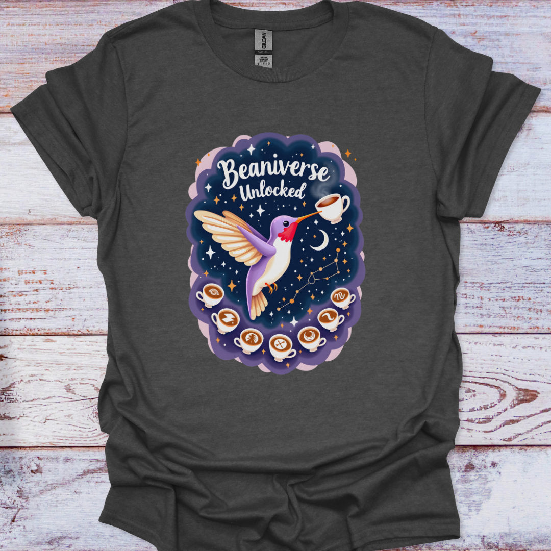 Dark gray t-shirt with a colorful graphic of a hummingbird, coffee cups, and 'Beaniverse Unlocked' text on a wooden surface.