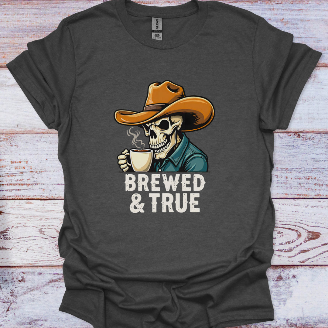 Dark gray t-shirt with a skeleton wearing a cowboy hat and holding a coffee cup, text 'BREWED & TRUE' on a wooden surface.