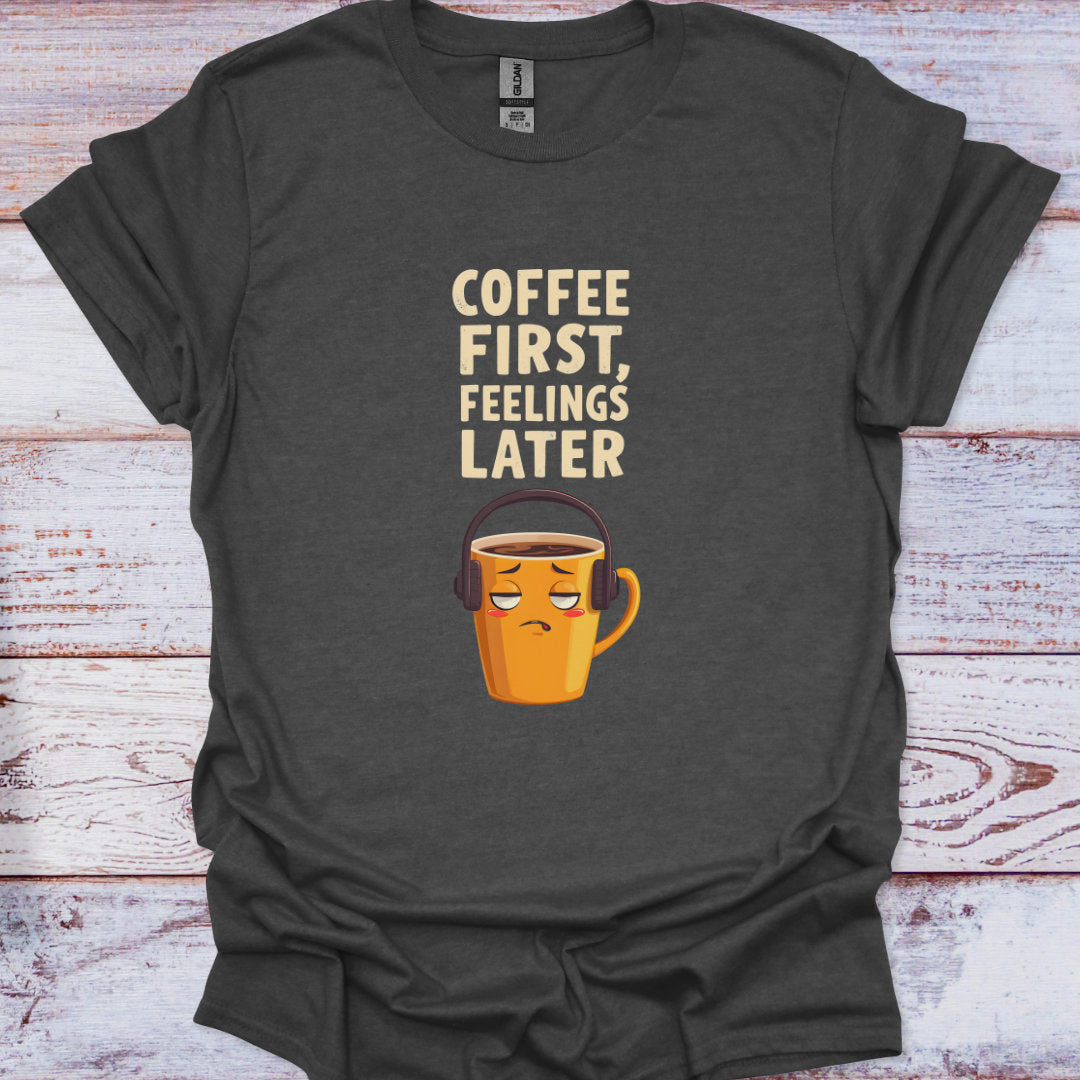 Dark gray t-shirt with a coffee cup graphic and text 'Coffee First, Feelings Later' on a wooden surface.