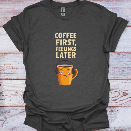 Dark gray t-shirt with a coffee cup graphic and text 'Coffee First, Feelings Later' on a wooden surface.
