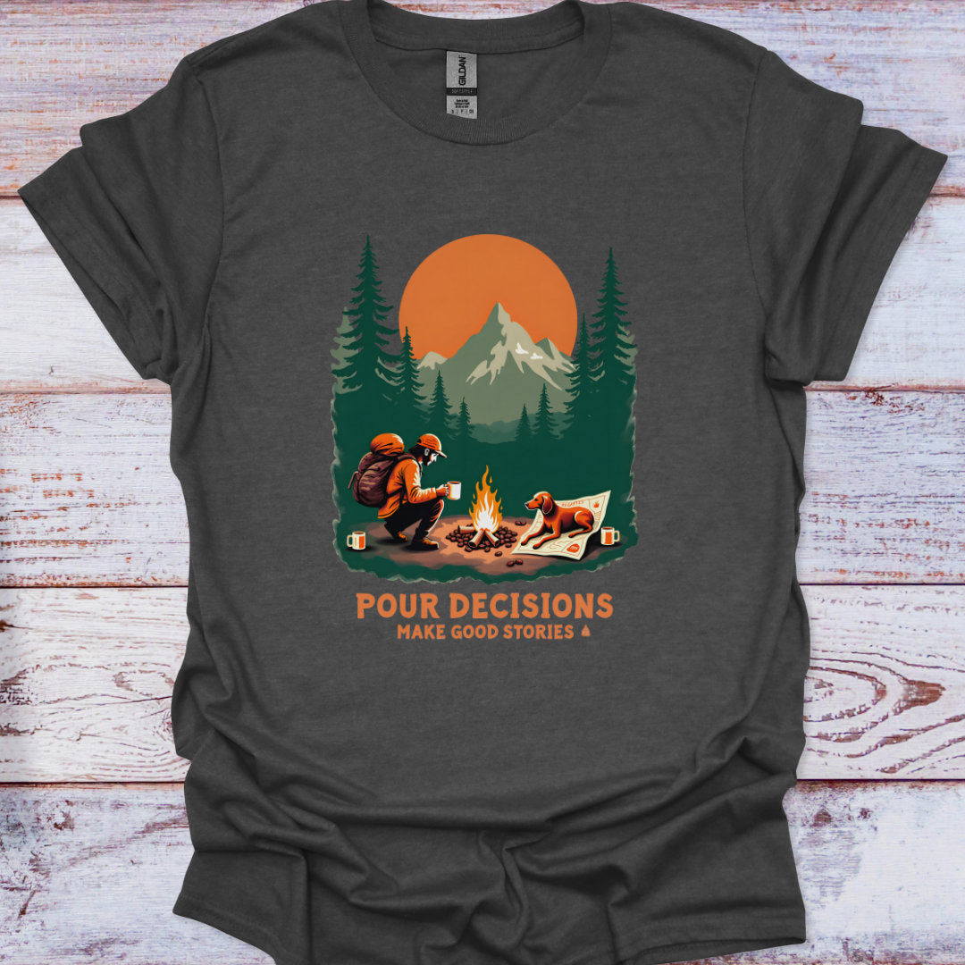 Dark gray t-shirt with a graphic of a man and his dog  by a campfire, mountains, and trees, with text 'Pour Decisions Make Good Stories' on a wooden surface.