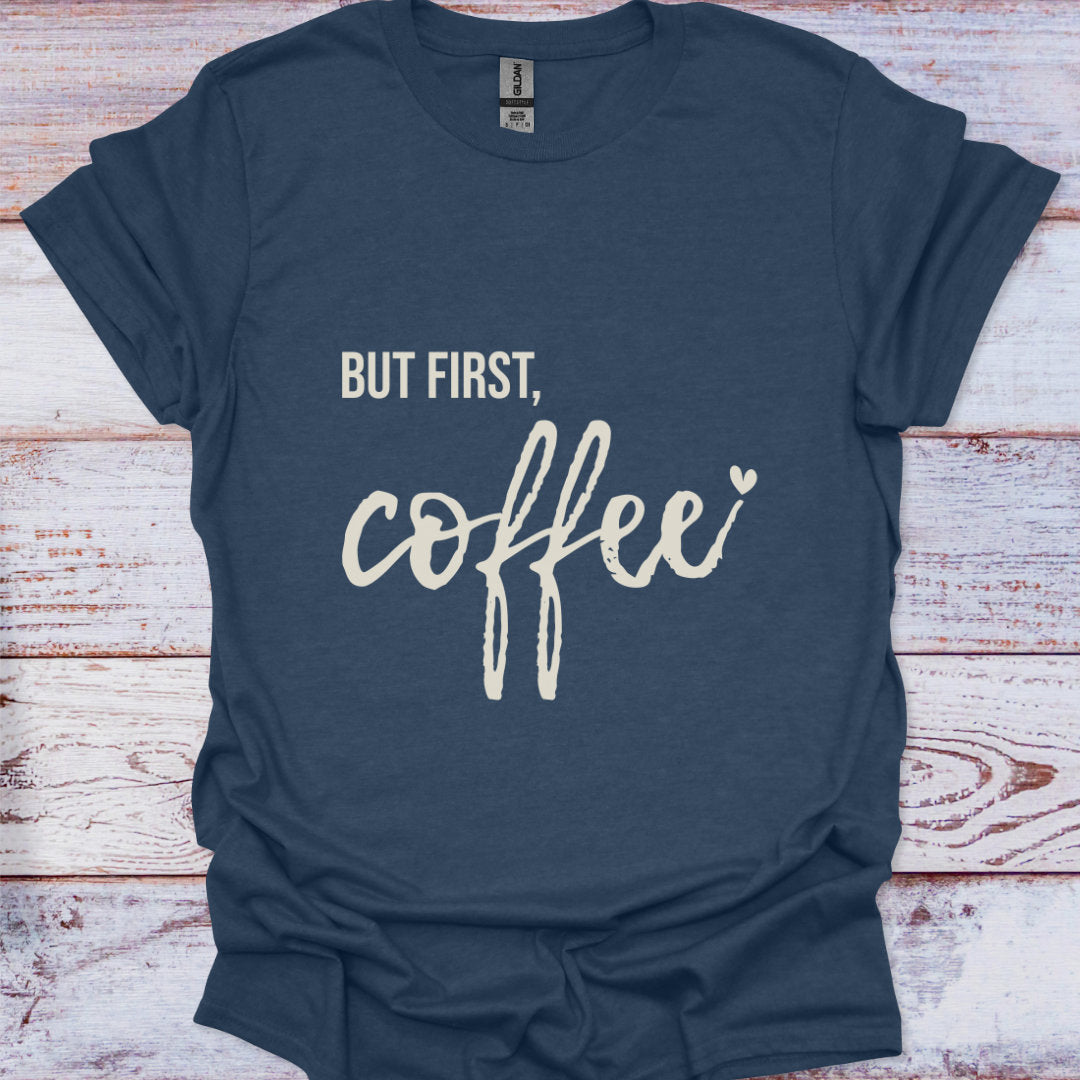 Navy blue t-shirt with 'But first, coffee' text on a wooden surface