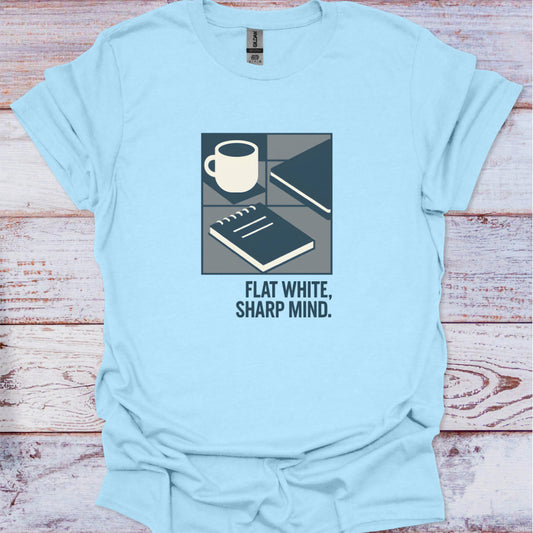 Light blue t-shirt with a graphic design and text 'Flat White, Sharp Mind' on a wooden surface.