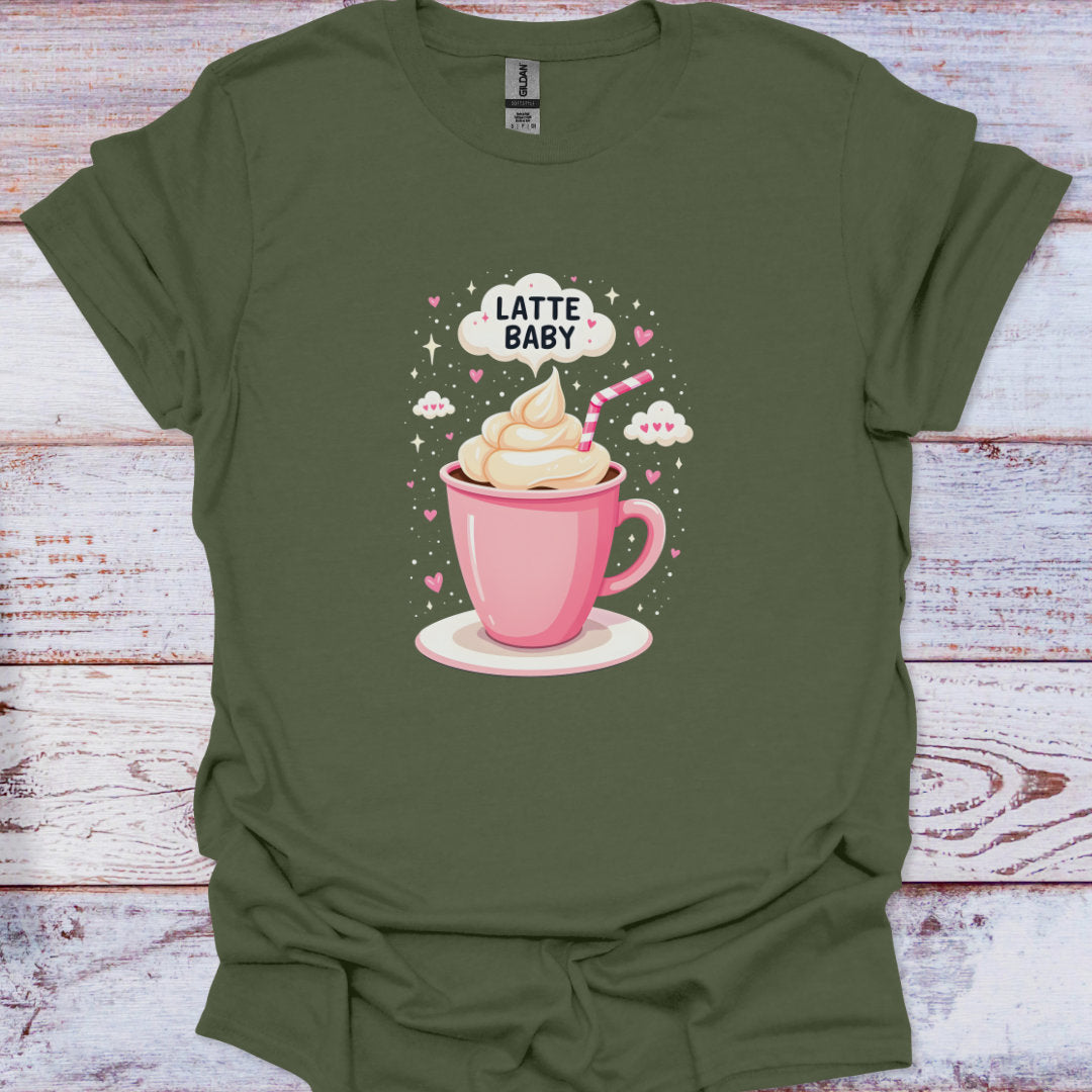 Green t-shirt with a graphic of a pink coffee cup with whipped cream and a straw, labeled 'Latte Baby', on a wooden surface.