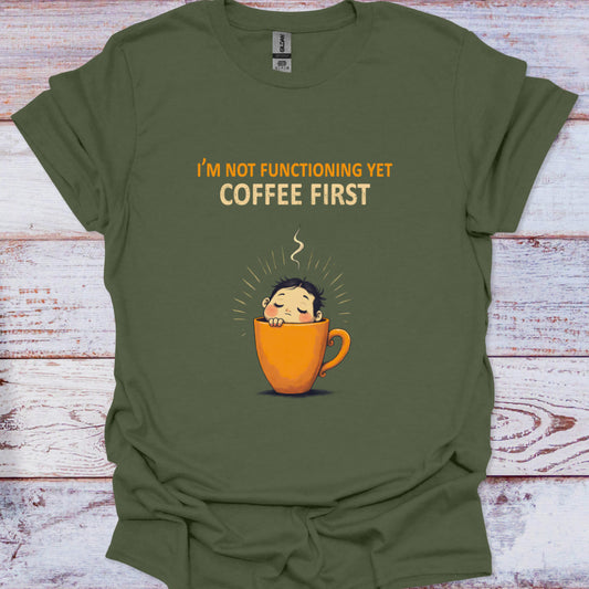 Green t-shirt with a coffee cup graphic and text 'I'm not functioning yet coffee first' on a wooden surface.