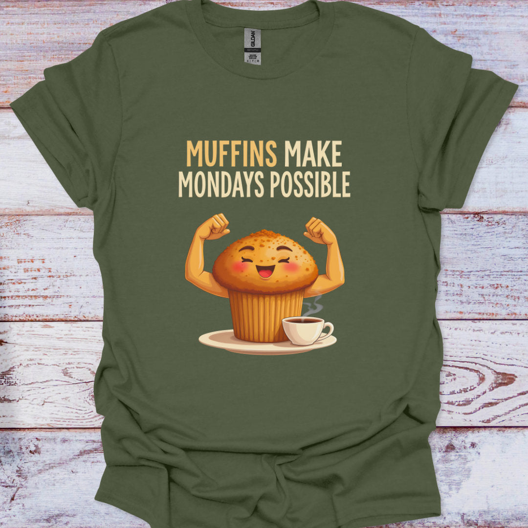 Green t-shirt with a cartoon muffin flexing muscles and text 'Muffins Make Mondays Possible' on a wooden surface.