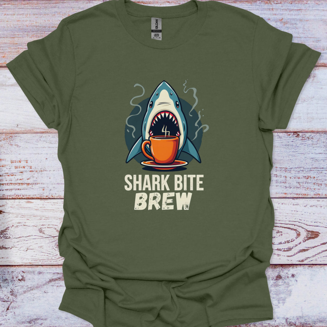 Green t-shirt with a shark drinking coffee graphic and 'Shark Bite Brew' text on a wooden surface.