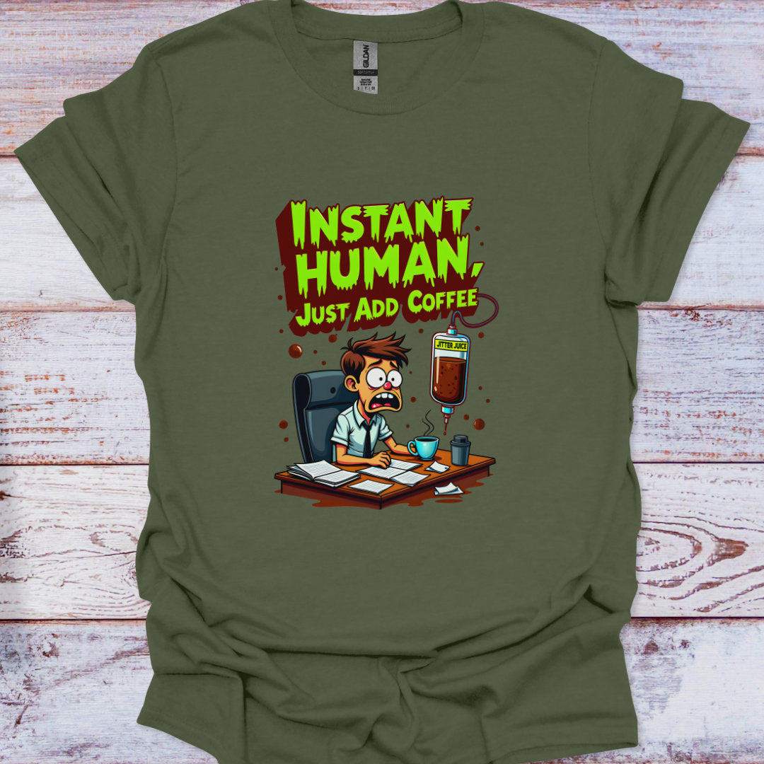 Green t-shirt with cartoon character and 'Instant Human, Just Add Coffee' text on a wooden surface