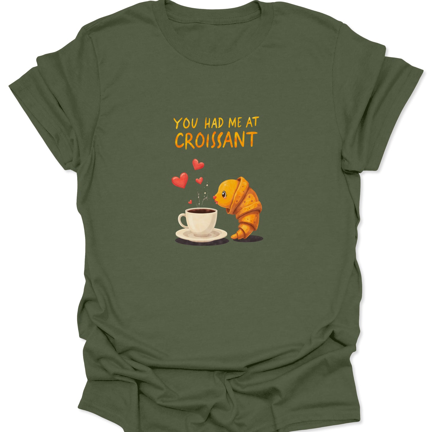Military green shirt for brunch enthusiasts, showing a yellow and orange croissant kissing a hot coffee cup. Ideal for Cross-Niche Foodie & Comfort designs.
