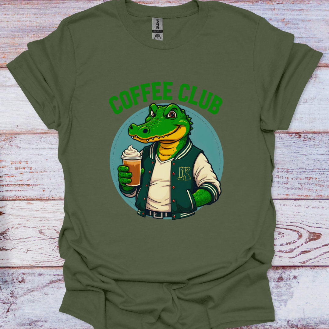 Green t-shirt with a cartoon alligator holding a coffee cup and 'Coffee Club' text on a wooden surface.