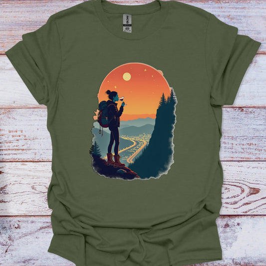 Green t-shirt with a graphic of a hiker and sunset design on a wooden surface