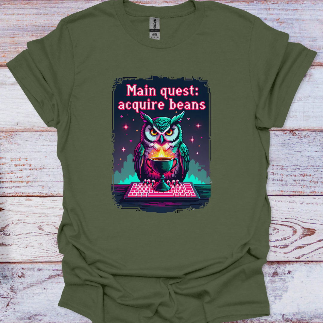 Green t-shirt with an owl graphic and text 'Main quest: acquire beans' on a wooden surface