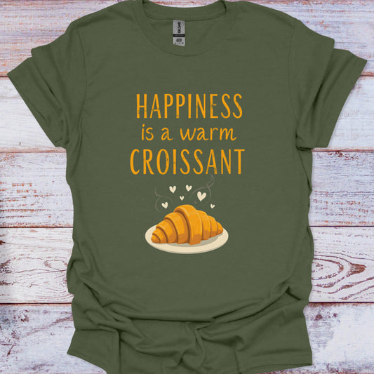 Green t-shirt with 'Happiness is a warm croissant' text and graphic on a wooden surface