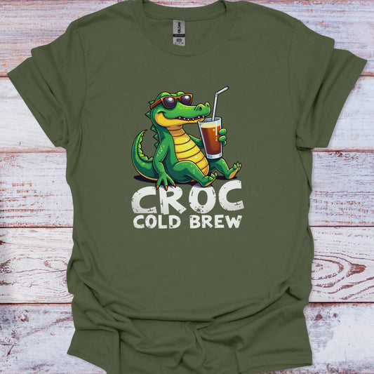Green t-shirt with a crocodile holding a cup labeled 'Croc Cold Brew' on a wooden surface.