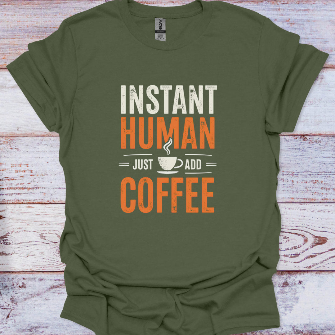 Green t-shirt with 'Instant Human Just Add Coffee' text on a wooden surface