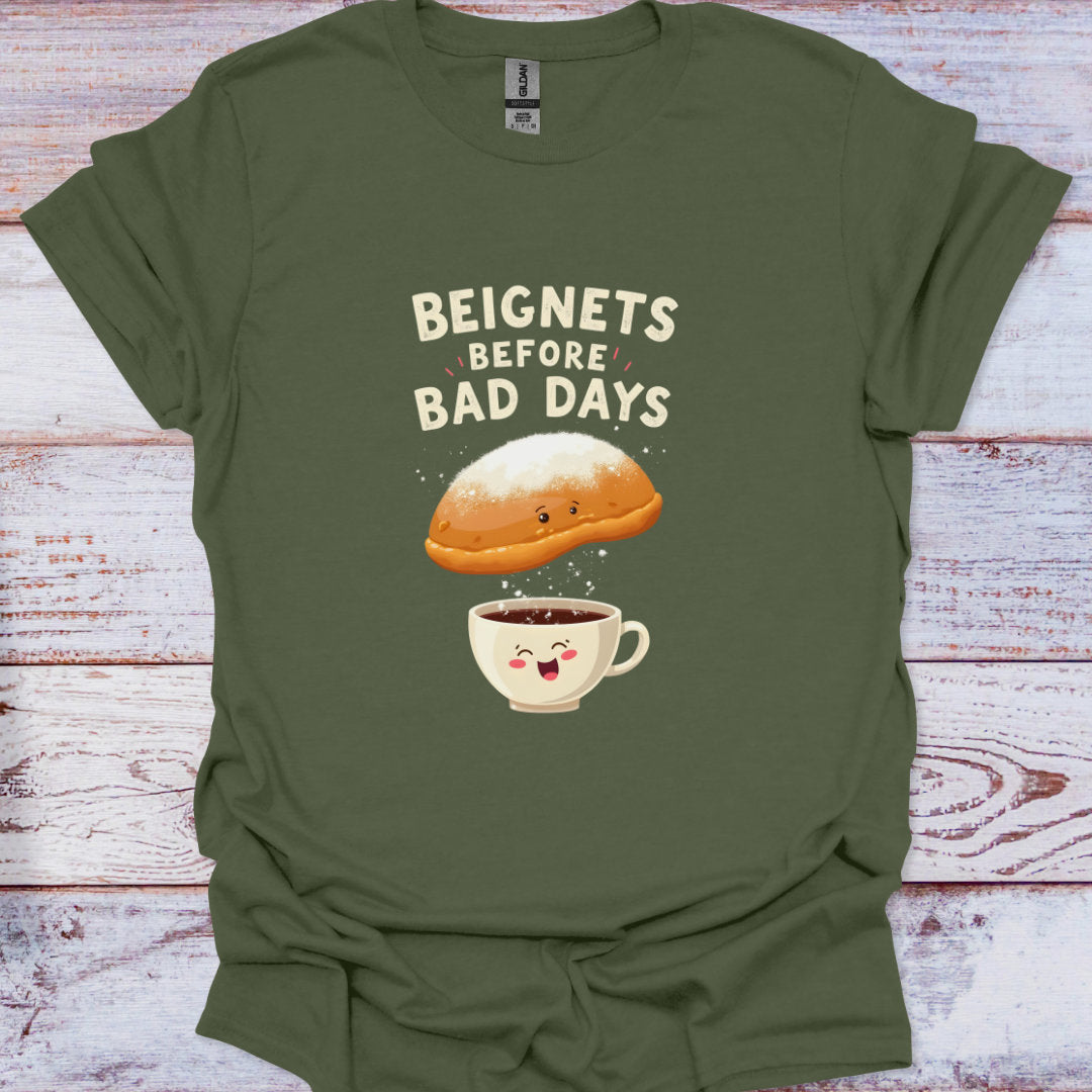 Green t-shirt with a graphic of a beignet and coffee cup with text 'Beignets Before Bad Days' on a wooden surface.