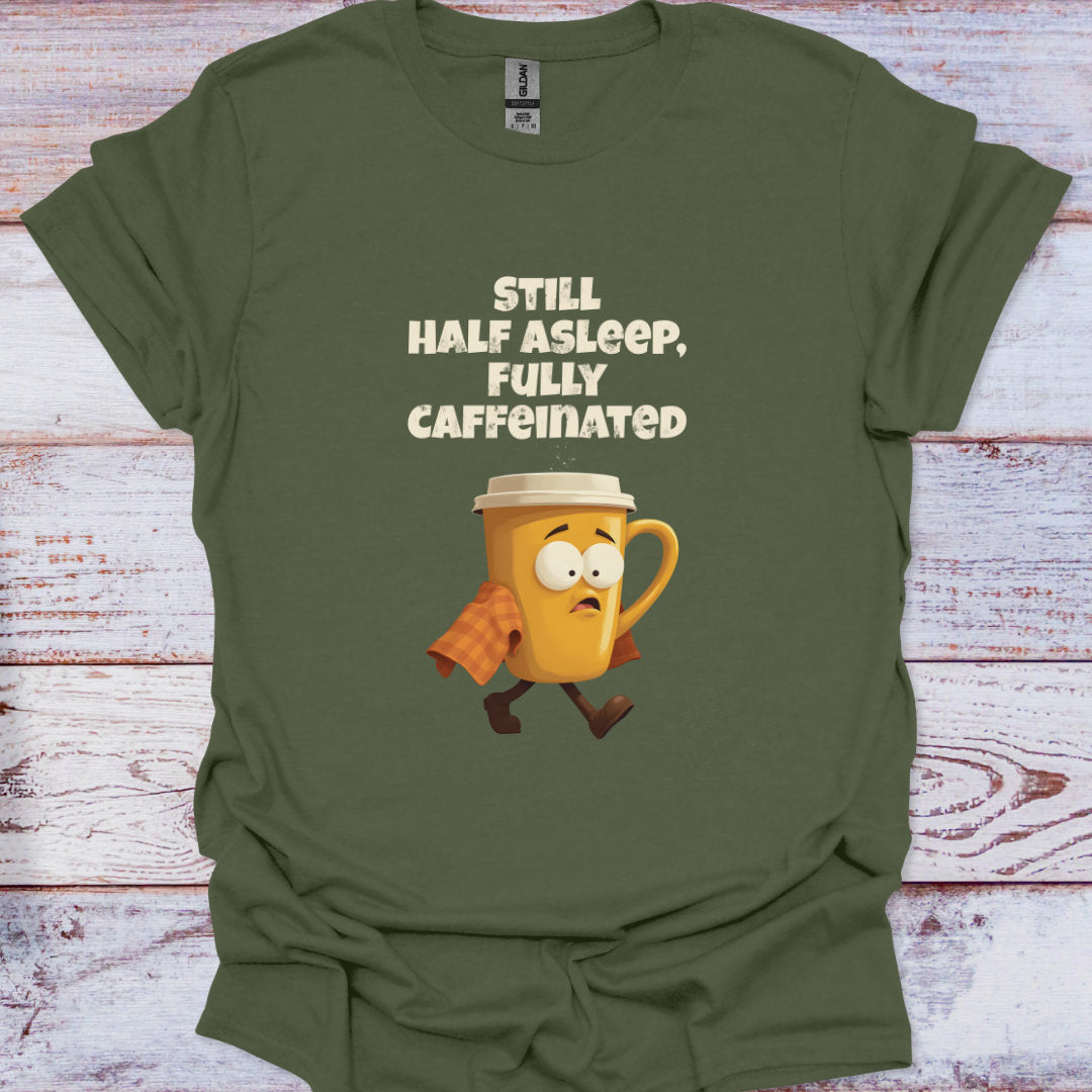 Green t-shirt with a cartoon coffee mug and text 'Still Half Asleep, Fully Caffeinated' on a wooden surface.