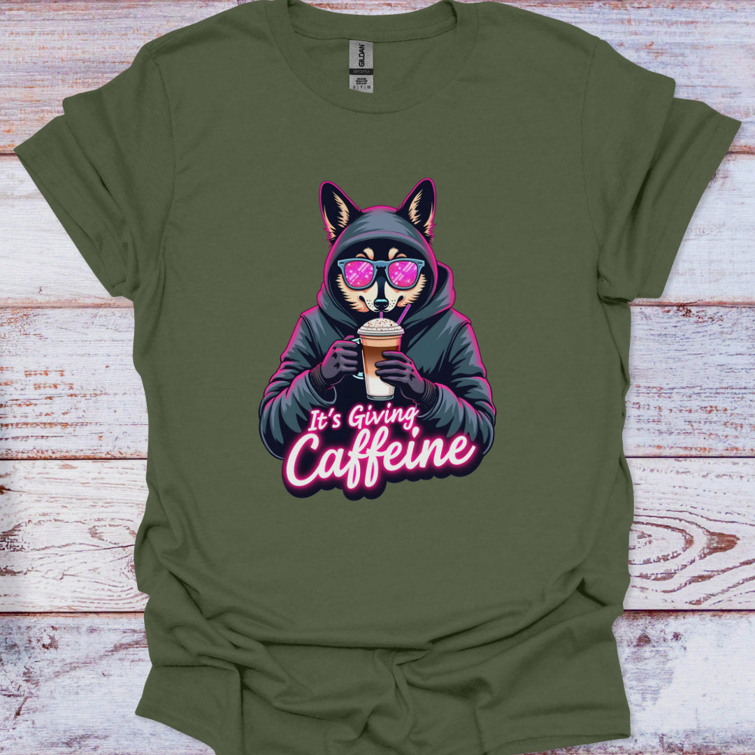 Green t-shirt with a graphic of a fox in a hoodie holding a coffee cup and text 'It's Giving Caffeine' on a wooden surface.