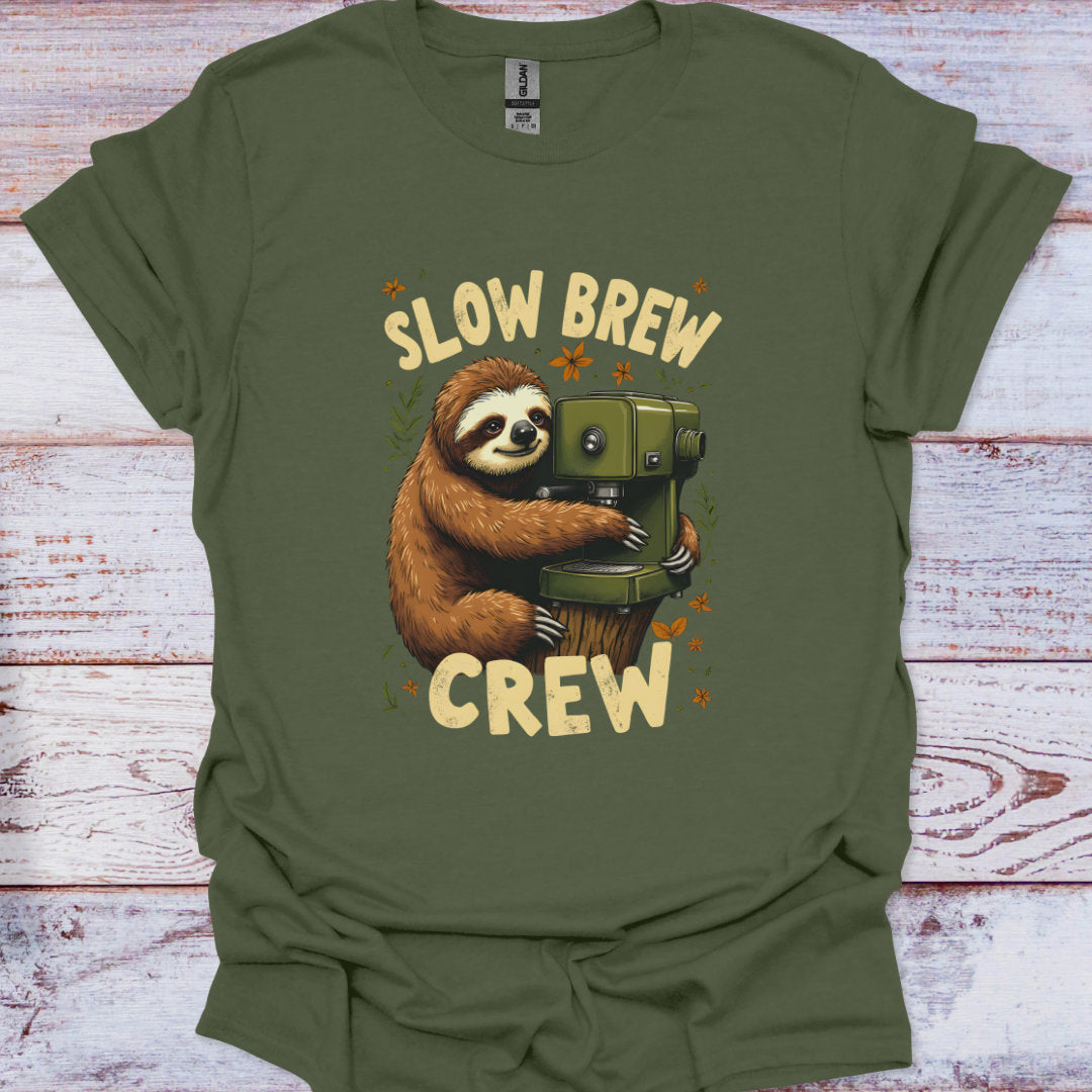 Green t-shirt with a sloth holding a coffee press and 'Slow Brew Crew' text on a wooden surface.