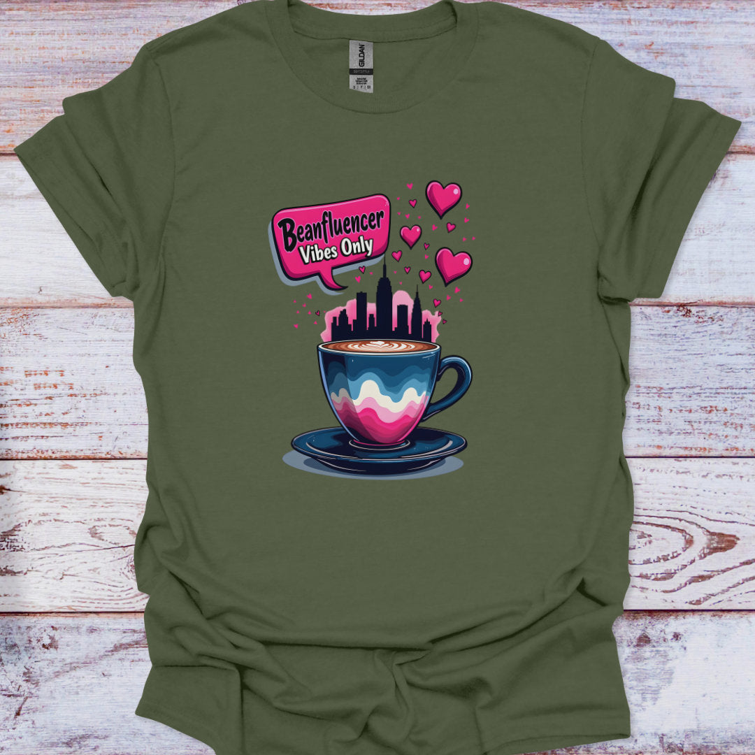 Green t-shirt with a colorful coffee cup graphic and 'Beanfluencer Vibes Only' text on a wooden surface.
