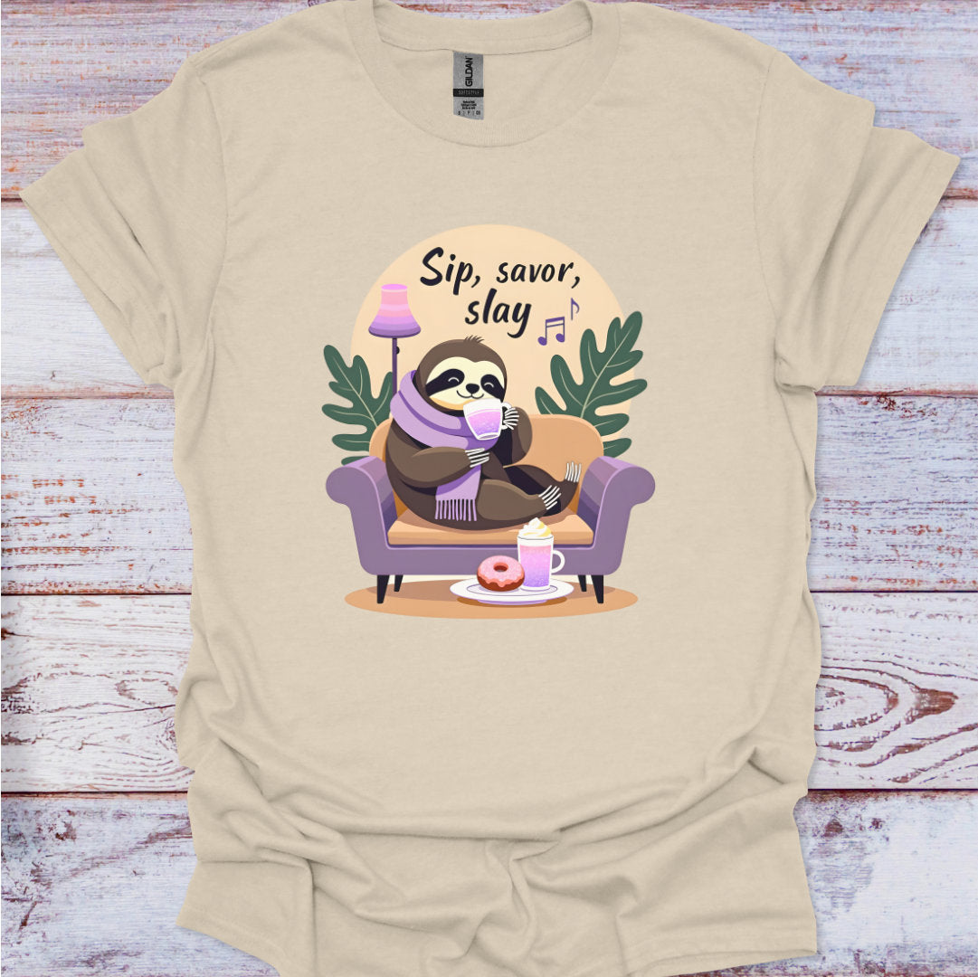 Beige t-shirt with a sloth graphic and 'Sip, savor, slay' text on a wooden surface