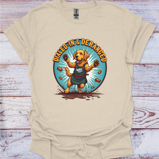 Beige t-shirt with a graphic of a dog and text 'Dialled-In & Deranged' on a wooden surface.