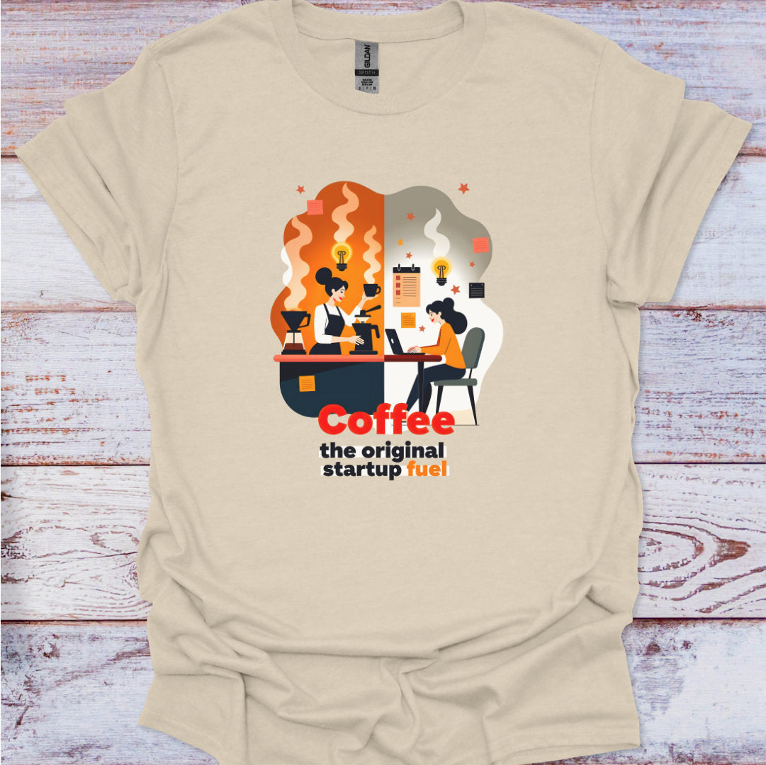 Beige t-shirt with a graphic design of people working at a desk with coffee cups, and text 'Coffee the original startup fuel' on a wooden surface.