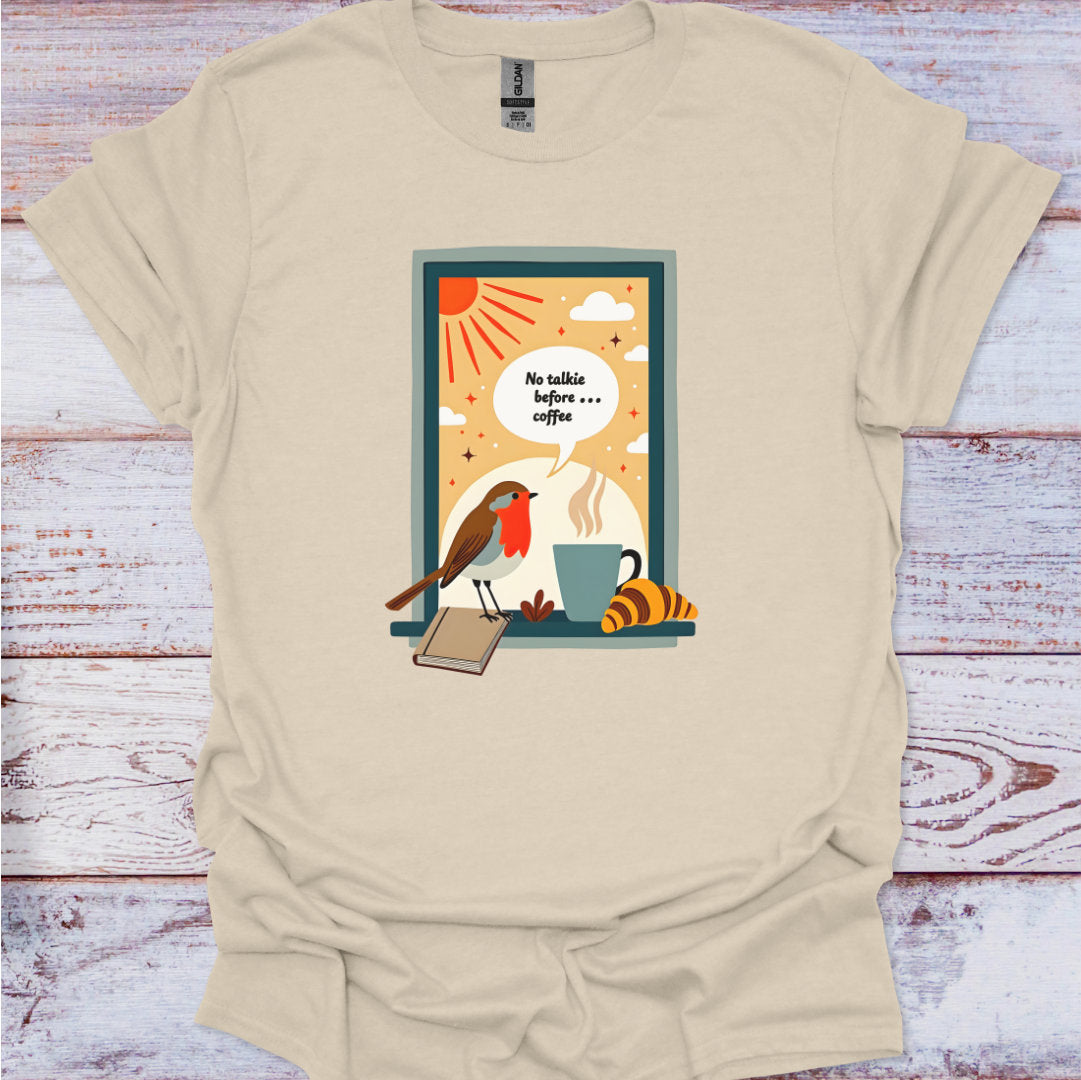 Beige t-shirt with a graphic design of a bird, coffee cup, and book on a wooden surface