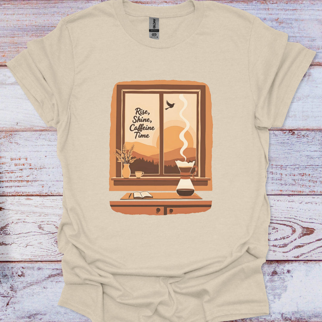 Beige t-shirt with a window graphic and 'Rise, Shine, Caffeine Time' text on a wooden surface.
