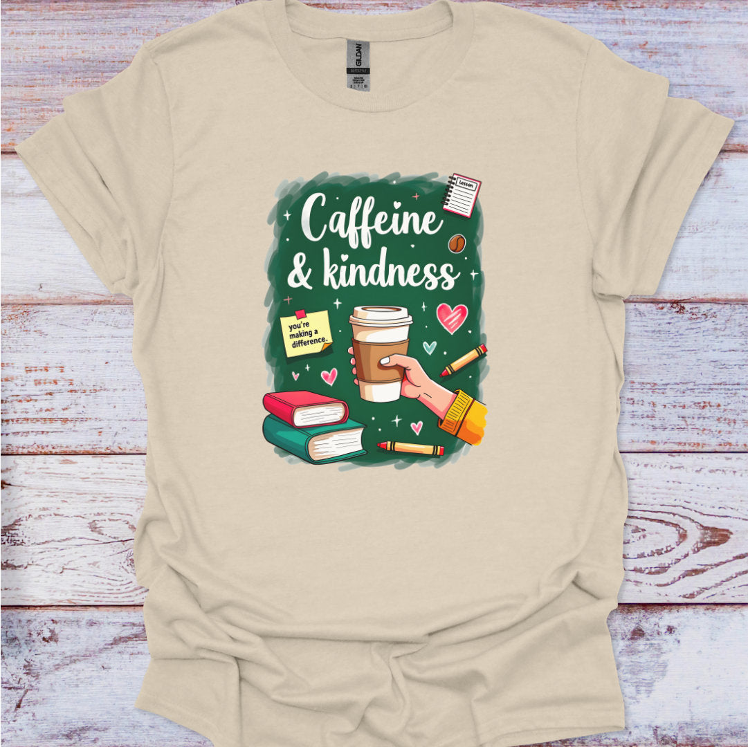 Beige t-shirt with a graphic design of a hand holding a coffee cup, books, and text 'Caffeine & kindness' on a wooden surface.