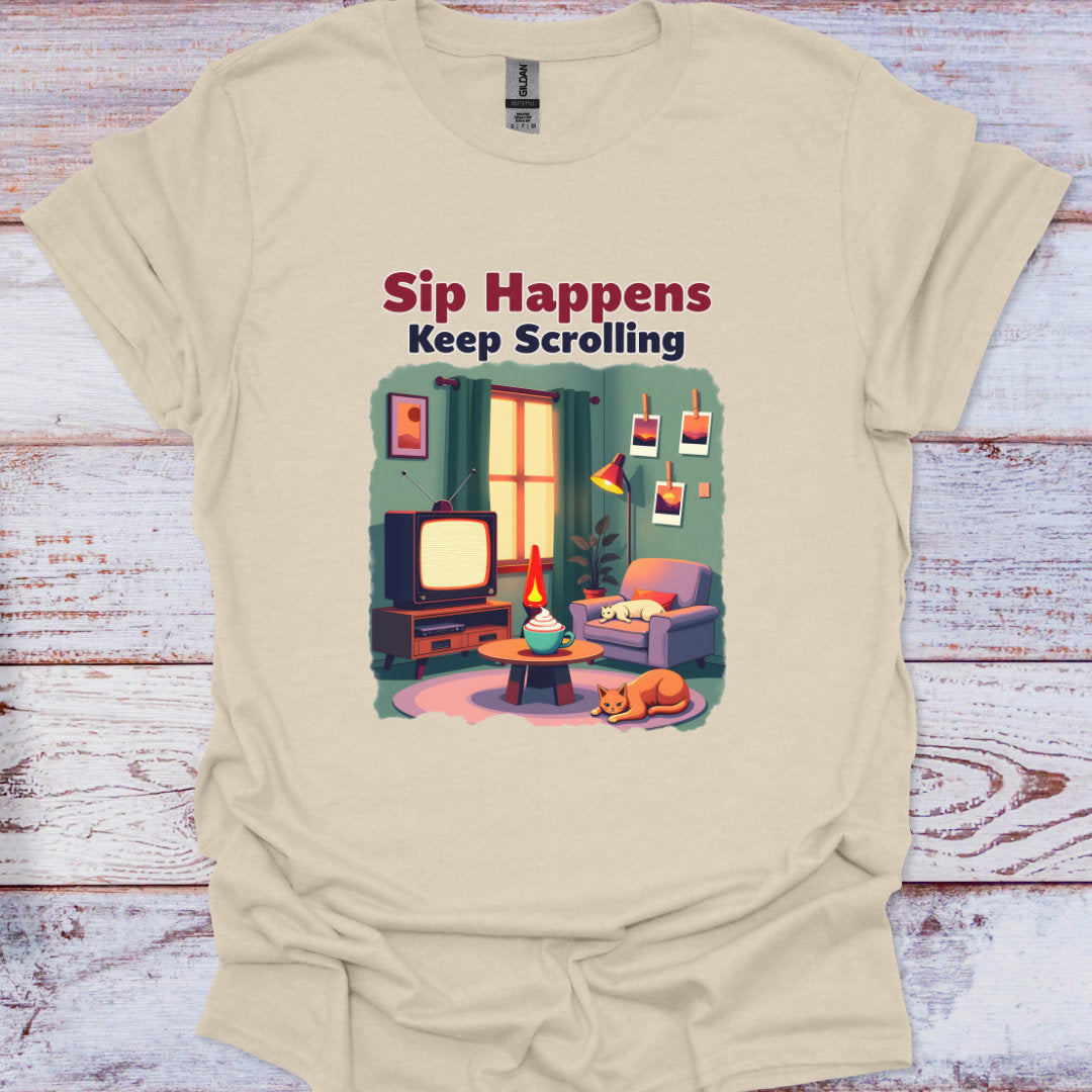 Beige t-shirt with a graphic of a living room scene and text 'Sip Happens Keep Scrolling' on a wooden surface.