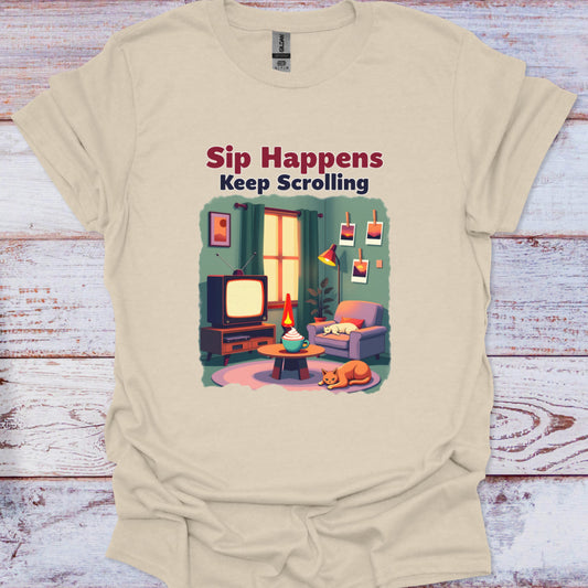 Beige t-shirt with a graphic of a living room scene and text 'Sip Happens Keep Scrolling' on a wooden surface.
