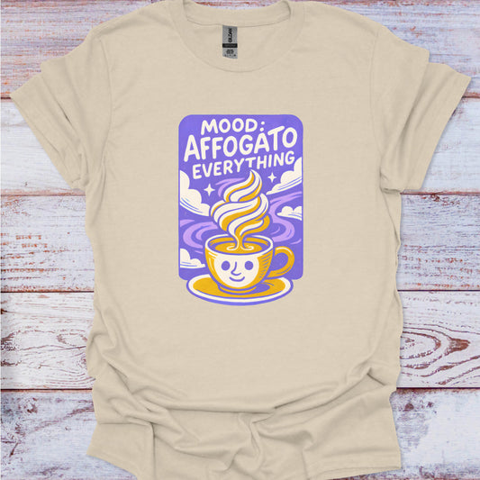 Beige t-shirt with a graphic design of a coffee cup and text on a wooden surface