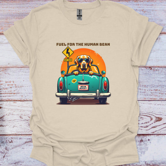 Beige t-shirt with a graphic of a dog in a car and text 'Fuel for the Human Bean' on a wooden surface.