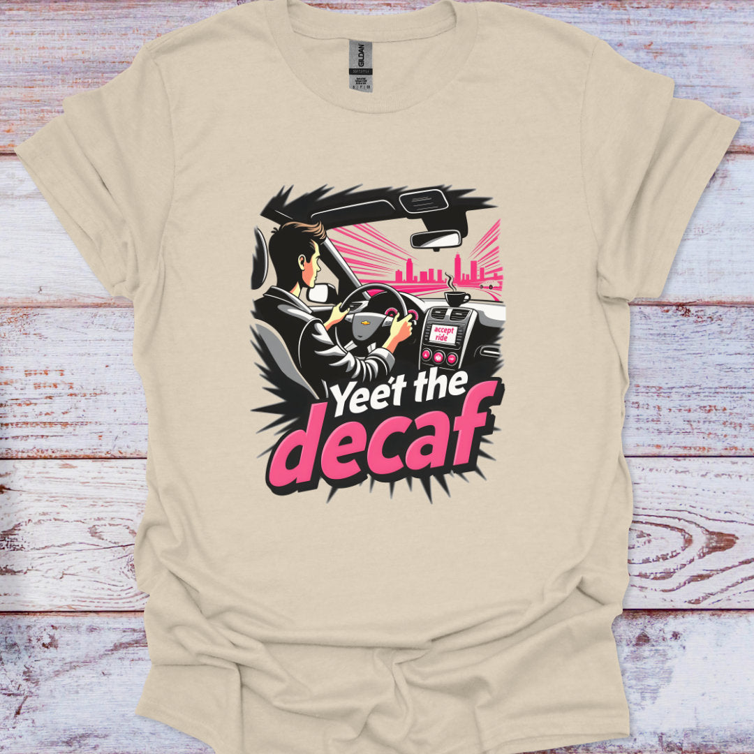 Beige t-shirt with a graphic design featuring a person driving a car and text 'Yeet the decaf' on a wooden surface.