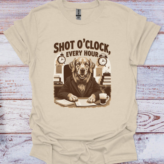 Beige t-shirt with a graphic of a dog at a desk and text 'Shot O'Clock, Every Hour' on a wooden surface.