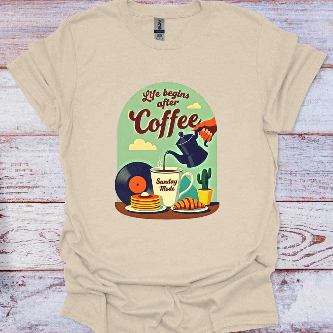 Beige t-shirt with a graphic design of 'Life begins after Coffee' on a wooden surface