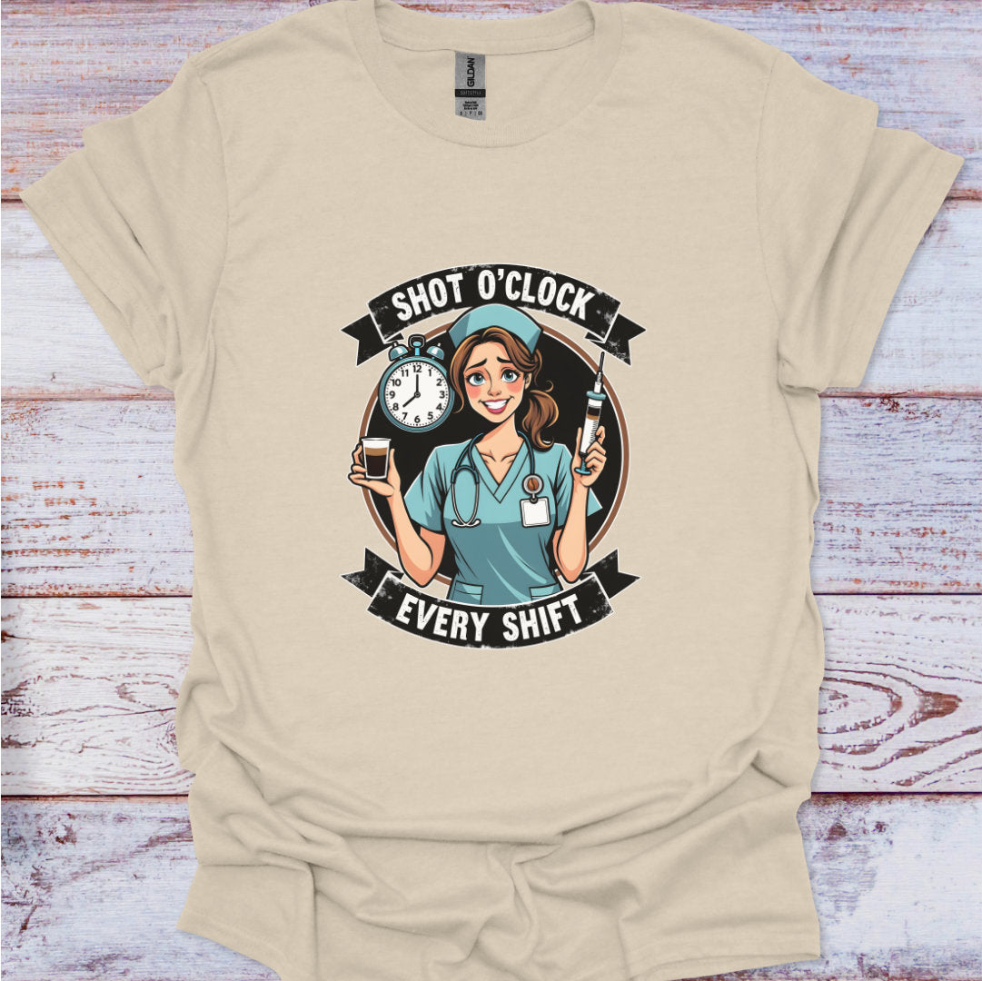 Beige t-shirt with a graphic of a nurse and text 'Shot O'Clock Every Shift' on a wooden surface.