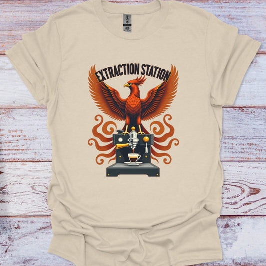 Beige t-shirt with a graphic of a mythic phoenix bird and coffee machine on a wooden surface