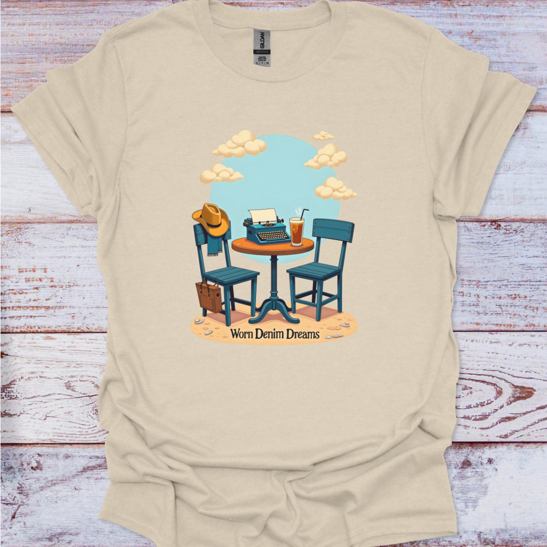 Beige t-shirt with a graphic of a table with chairs, a hat, and a drink on a wooden surface.