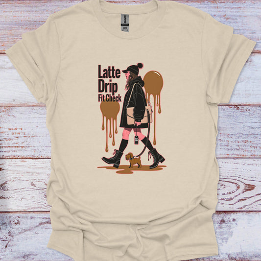 Beige t-shirt with graphic design of a woman walking a dog and 'Latte Drip Fit Check' text on a wooden surface.