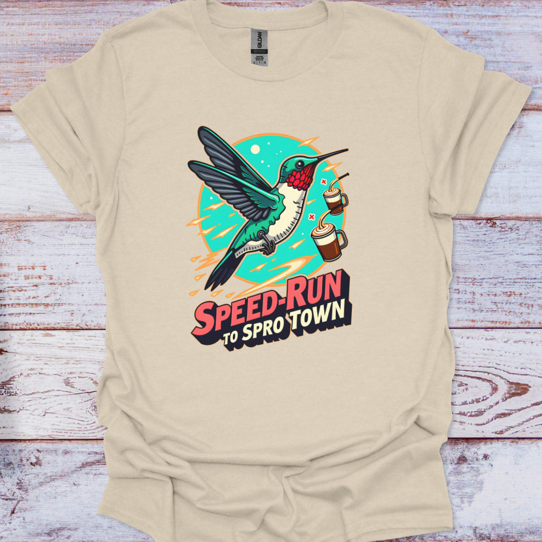 Beige t-shirt with a colorful graphic of a hummingbird and text on a wooden surface